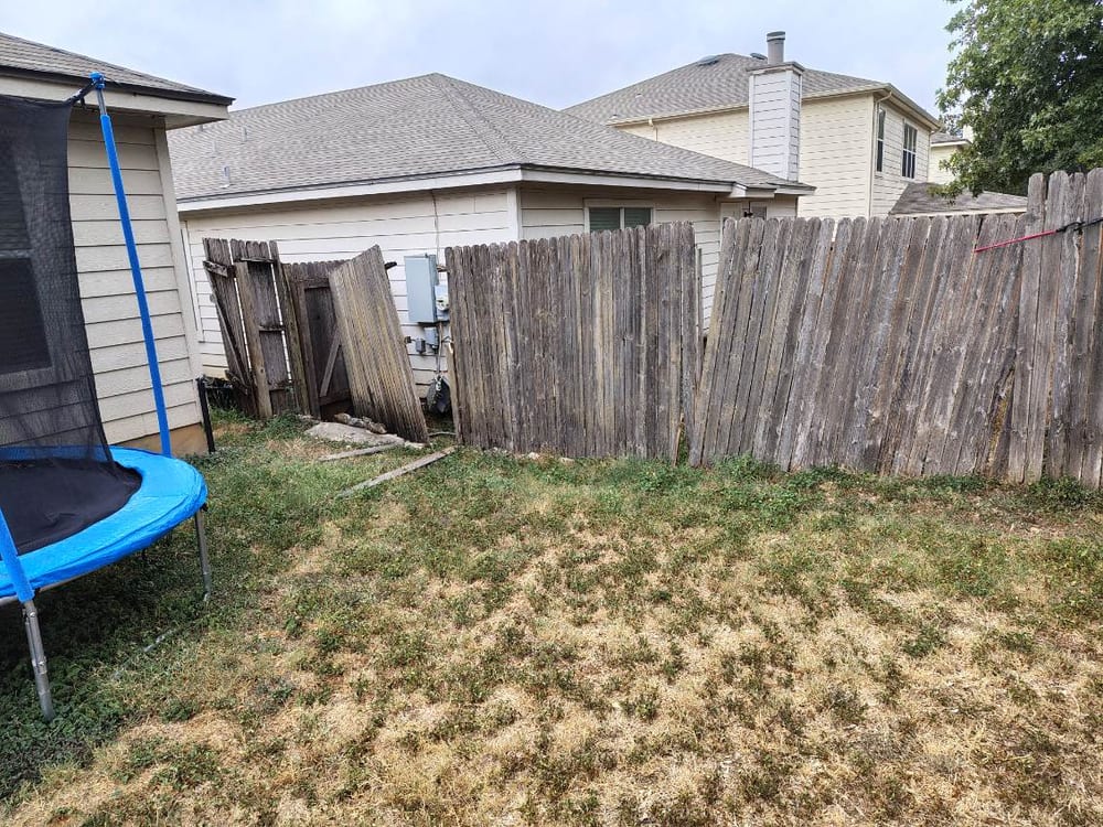 Old, weathered, leaning wood fence before replacement