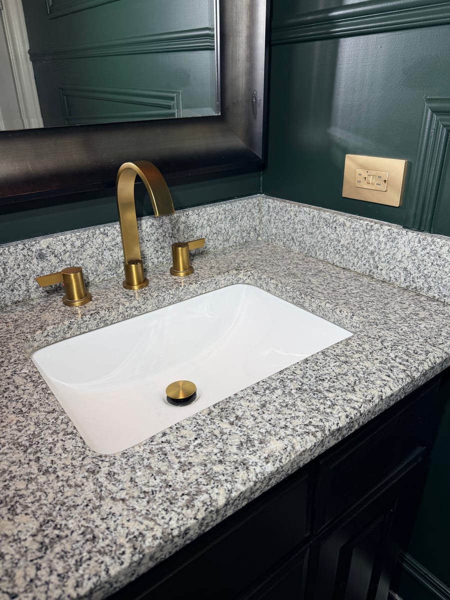 Brushed-brass faucet on a granite vanity in a remodeled powder room (project photo 8)